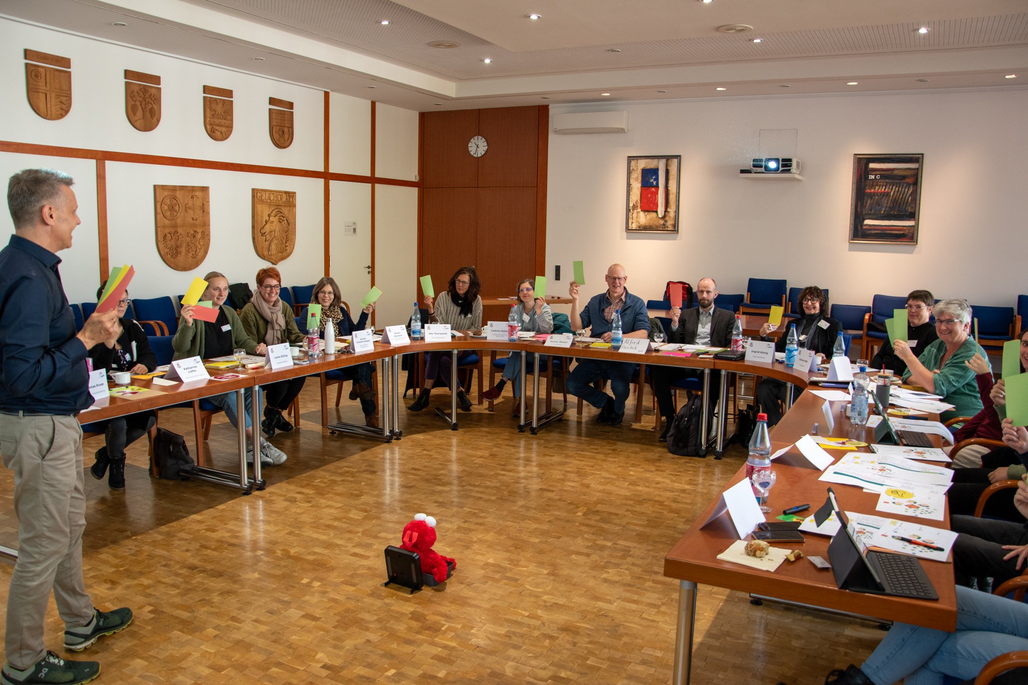 Auf dem Bild erkennt man eine Vielzahl von Personen, die in einer "Hufeisen-Formation" sitzen. Im Vordergrund steht ein Dozent.