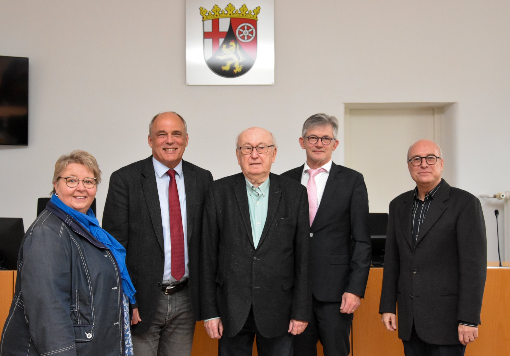 Auf dem Bild sieht man eine Gruppe von fünf Personen, die in einem Gerichtssaal stehen