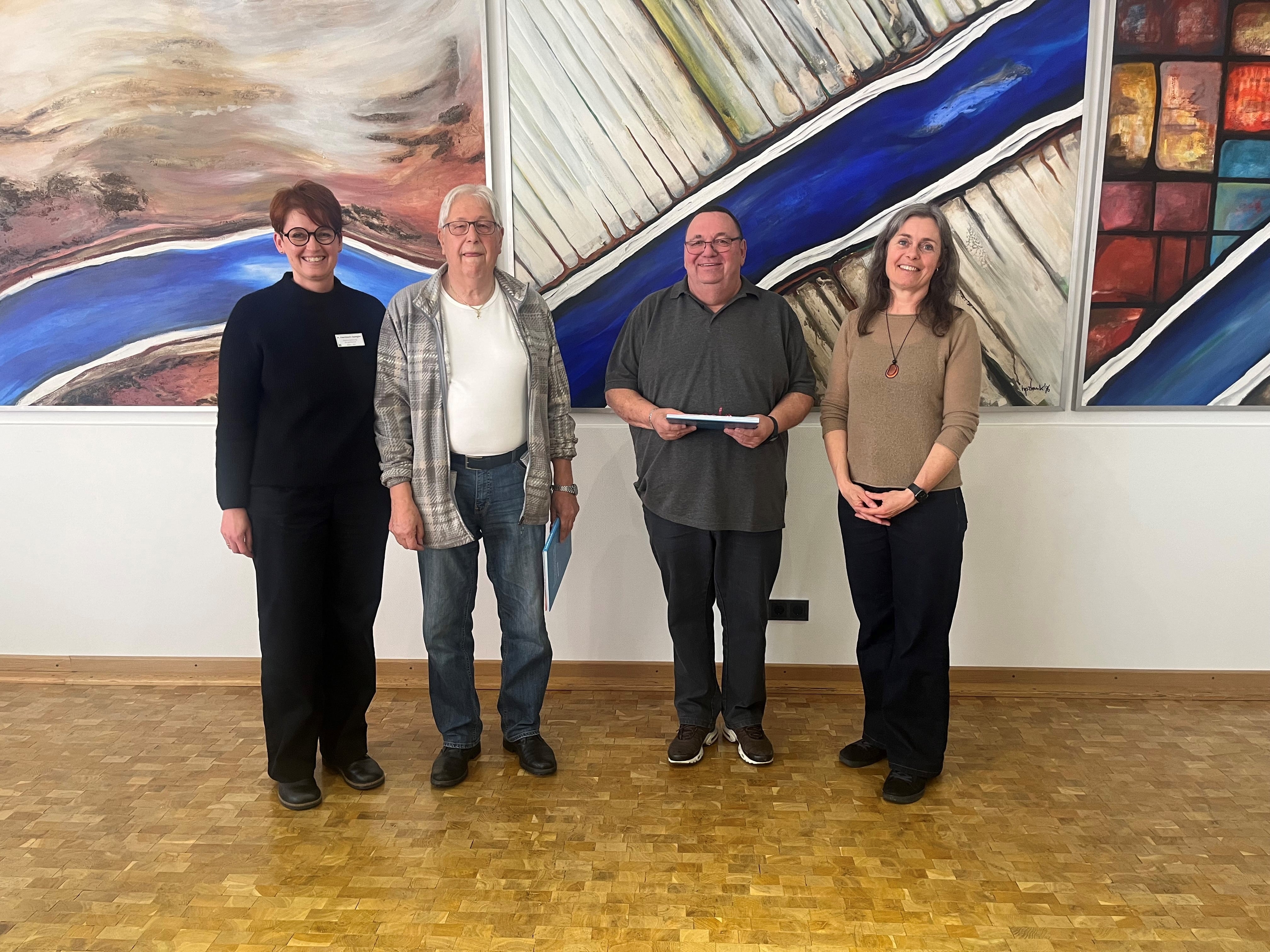 Auf dem Bild erkennt man vier Personen, die lachend in die Richtung der Betrachter blicken.