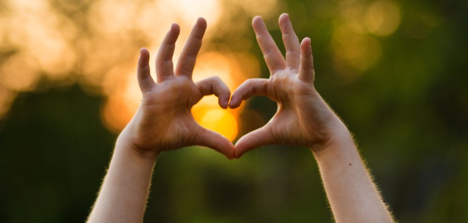 Ein Kind formt mit den Händen ein Herz.