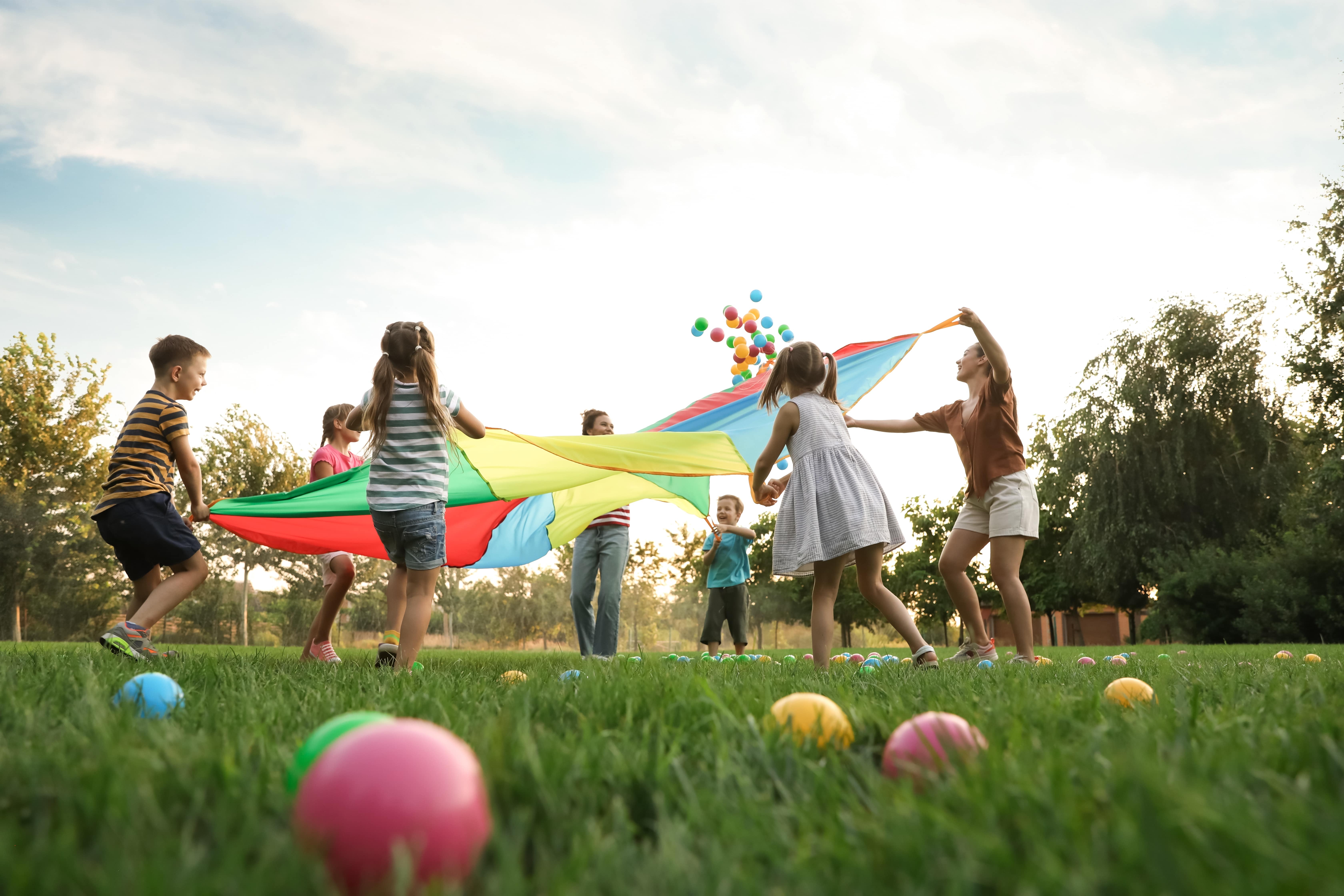 Ferienprogramm Auf dem Foto sieht man spielende Kinder auf einer grünen Wiese.