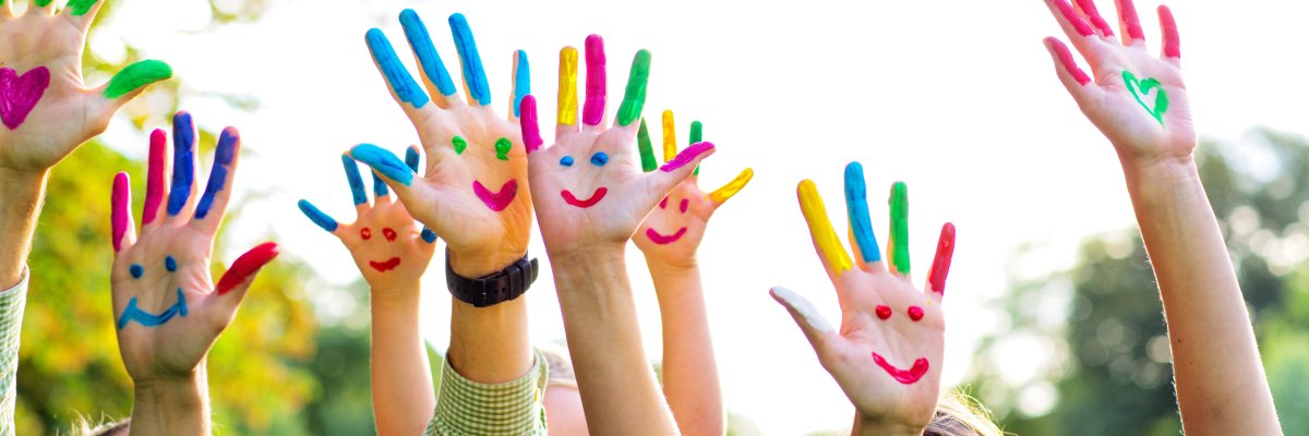 Bunte Kinderhände Auf dem Bild erkennt man Kinderhände. Diese sind bunt bemalt und man erkennt mehrere lachende Gesichter.