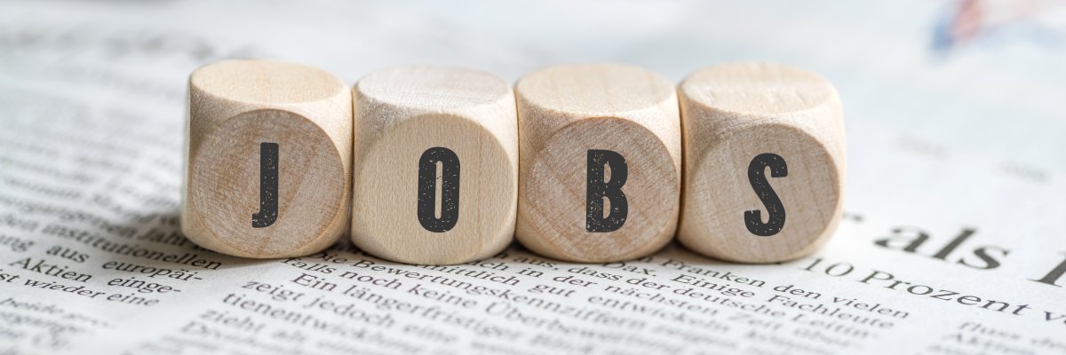 Würfel mit Aufschrift JOBS auf einer Tageszeitung Stellenangebote