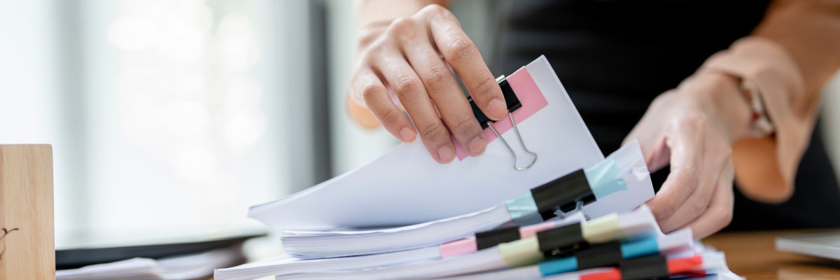 Businesswoman hands working in Stacks of paper files for searchi Verwaltungsberuf
