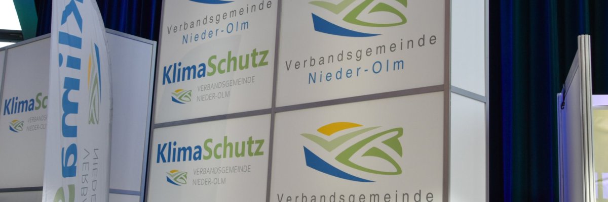 Auf dem Foto erkennt man eine Messewand, auf welchem das Logo des VG-Klimaschutz abgebildet ist.