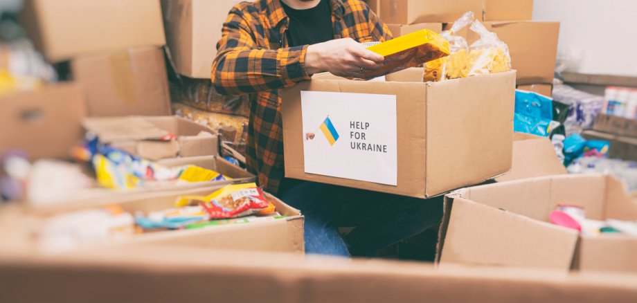 Auf dem Foto erkennt man eine Menge Kartons. Zentral ist ein Karton zu sehen, auf welchem "Help for Ukraine" geschrieben steht