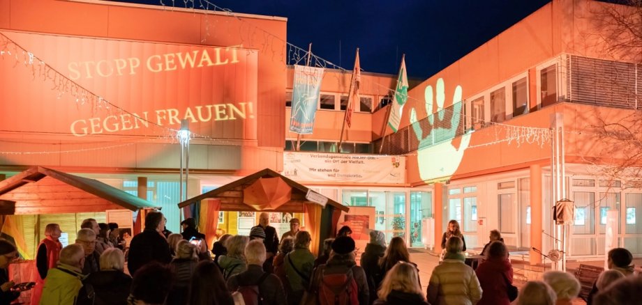 Auf dem Foto erkennt man einen orange erleuchteten Marktplatz auf welchem sich viele Menschen versammelt haben