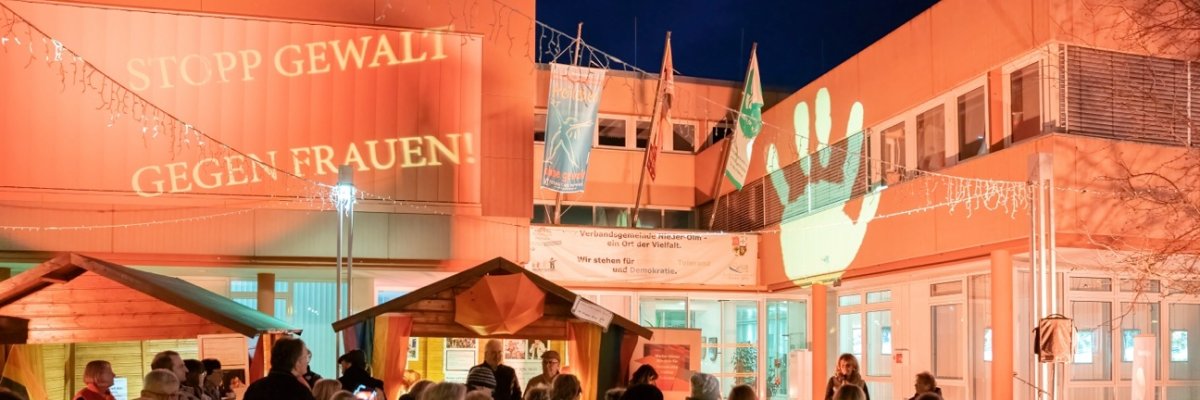 Auf dem Foto erkennt man einen orange erleuchteten Marktplatz auf welchem sich viele Menschen versammelt haben