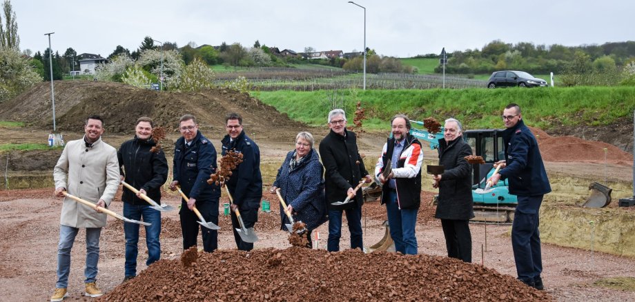 Auf dem Bild erkennt man Menschen mit Schaufeln, die auf einer Baustelle stehen.
