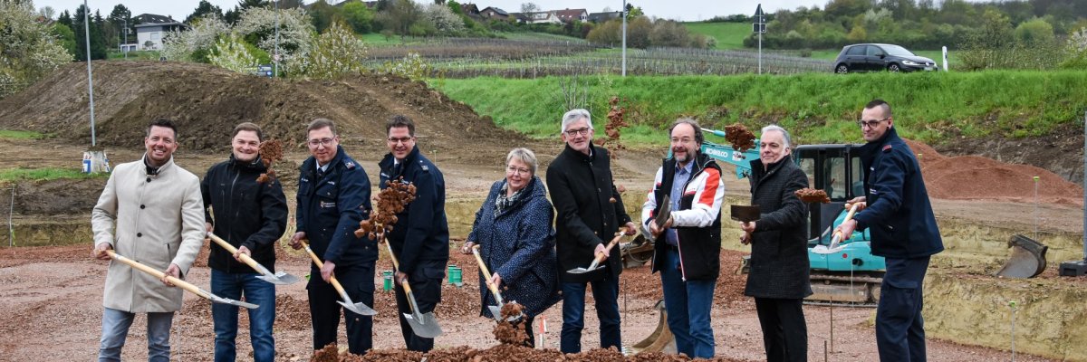 Auf dem Bild erkennt man Menschen mit Schaufeln, die auf einer Baustelle stehen.