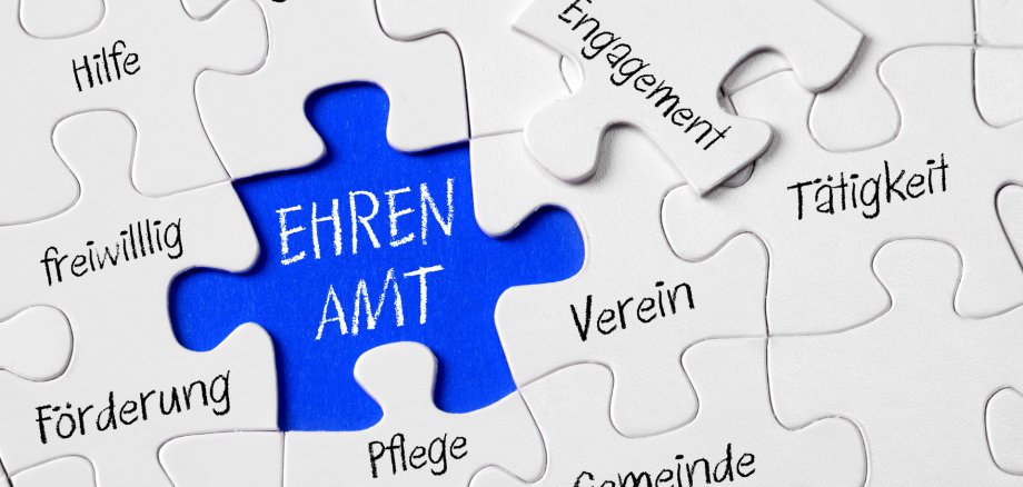 Auf dem Foto erkennt man ein Puzzle. In der Mitte ist ein blaues, freies Feld, in welchem "Ehrenamt" steht. Drum Herum stehen Begriffe wie sozial, Verein, Gemeinde, Tätigkeit.