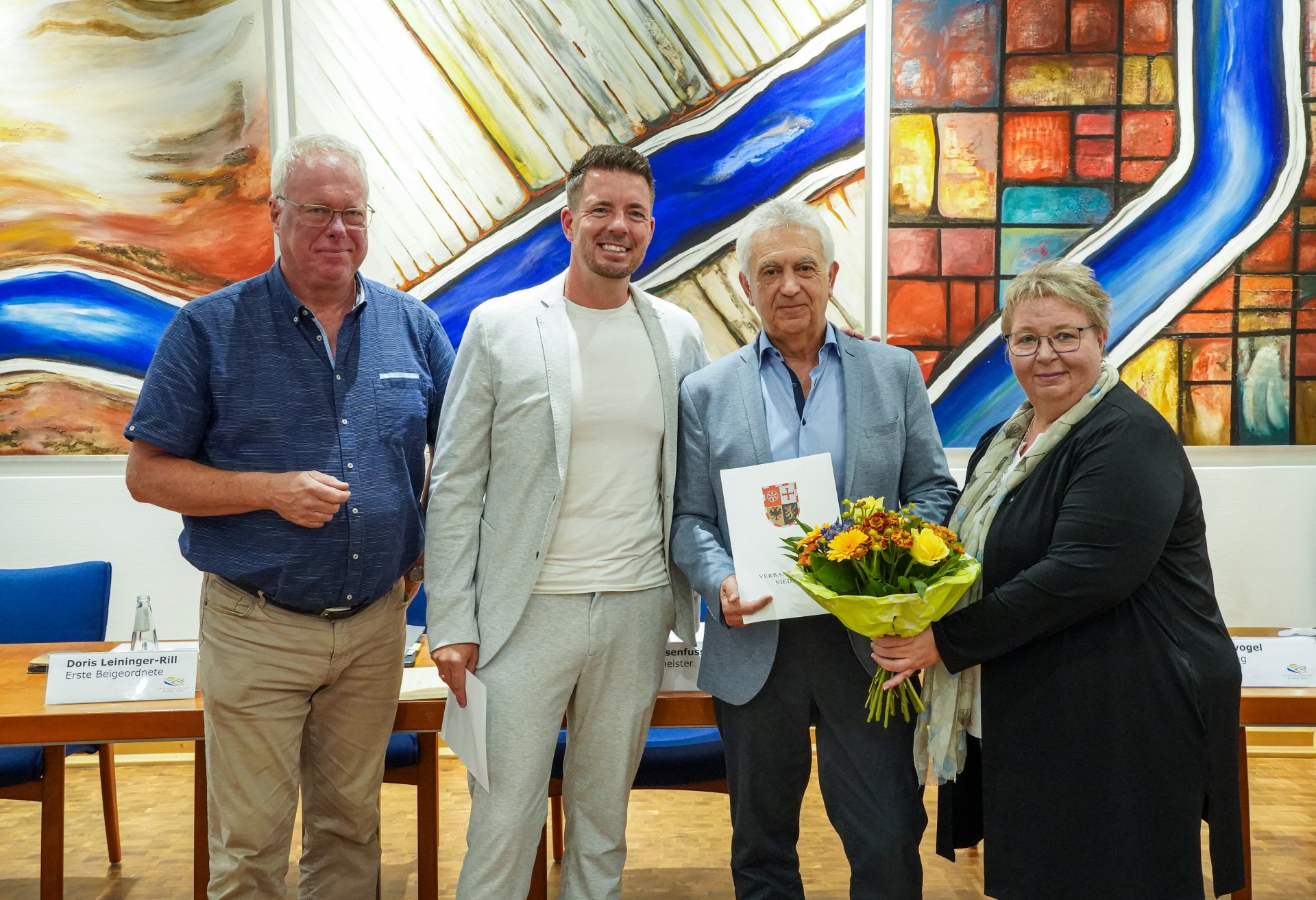 Vier Personen stehen nebeneinander und lachen freudig in die Kamera
