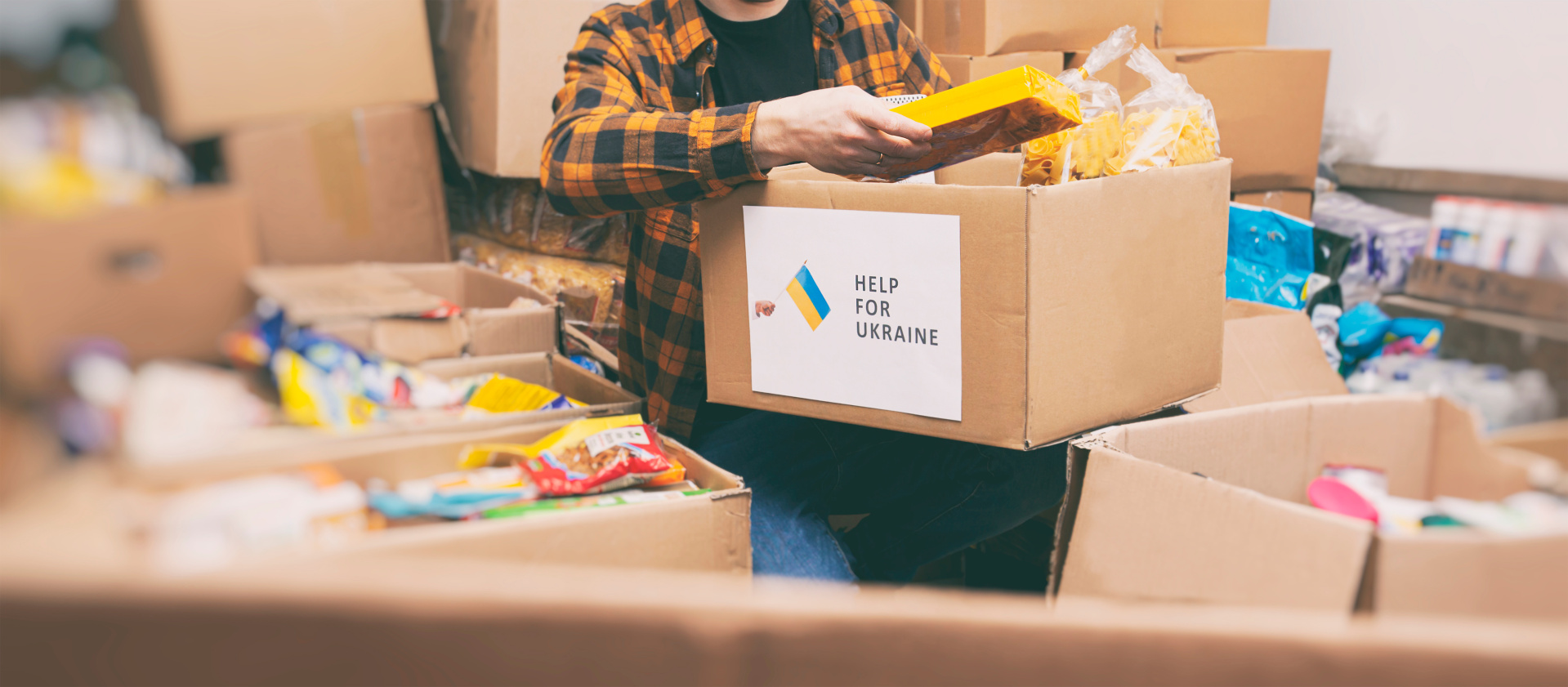 Auf dem Foto erkennt man eine Menge Kartons. Zentral ist ein Karton zu sehen, auf welchem "Help for Ukraine" geschrieben steht